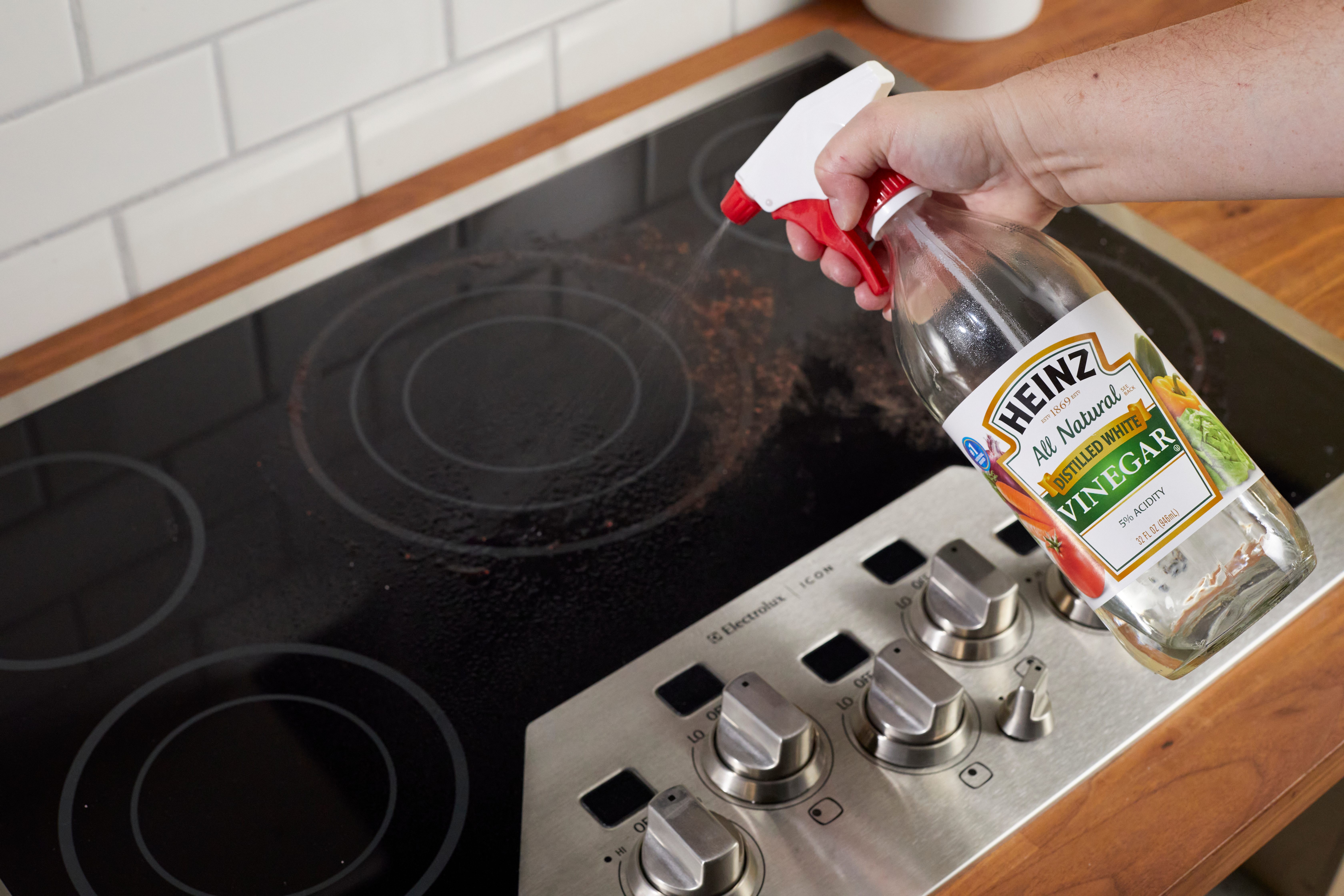 Baking soda and vinegar mixture fizzing on a glass stove top, demonstrating a natural cleaning solution