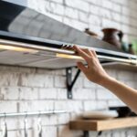 Person turning on range hood to ventilate kitchen
