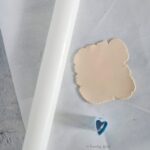 Rolling out beige polymer clay to make miniature heart cookies