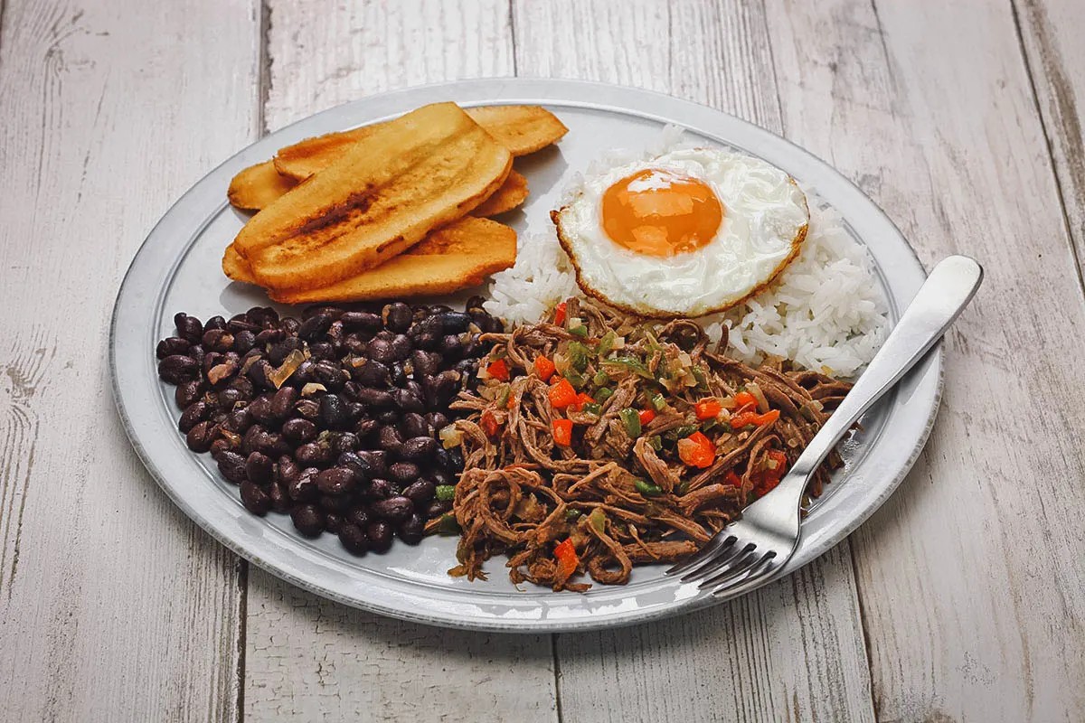 A plate of Pabellon Criollo, showcasing its distinct components of shredded beef, black beans, rice, and fried plantains