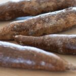 Close-up of freshly harvested yucca roots showing their rough, bark-like skin, essential for understanding their preparation requirements.